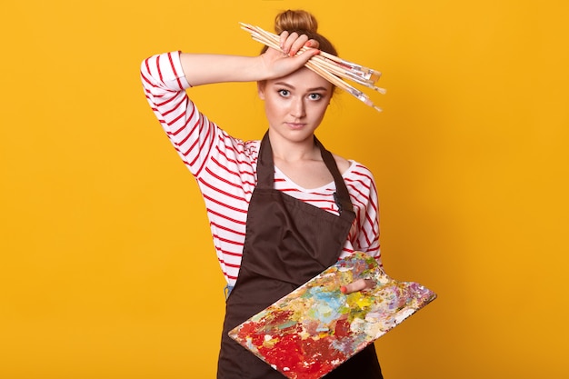 Picture of exhausted painter touching her forehead with hand