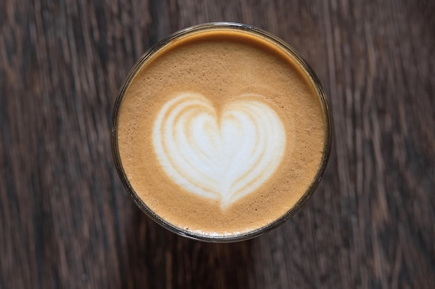 Picture in form a heart in the cup of coffee on a wooden background View from above