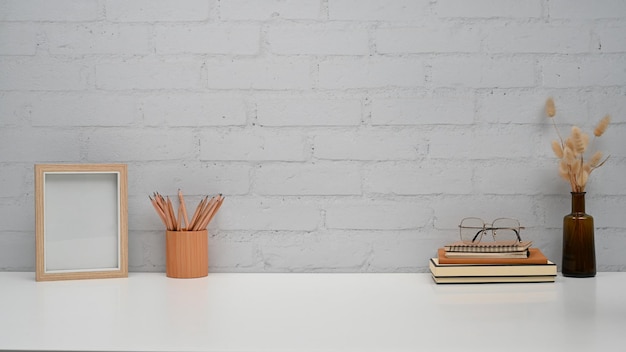 Picture frame pencil holder book and dried flower pot on white table