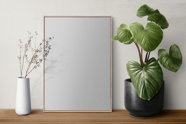 Picture frame png mockup op een plank met planten tegen een muur