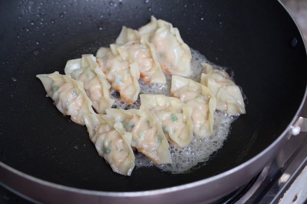 Picture of fried dumplings Gyozas with pork being cooked in a pan