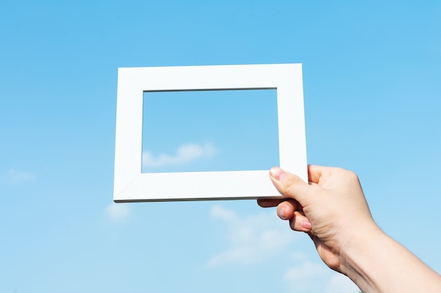 Picture of hands holding photo frames on blue sky background