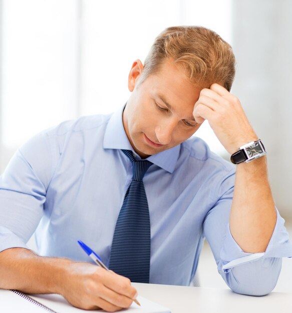 picture of handsome businessman writing in notebook