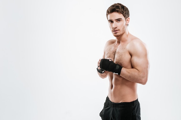 Изображение красивого боксера молодого человека, стоящего над белой стеной.
