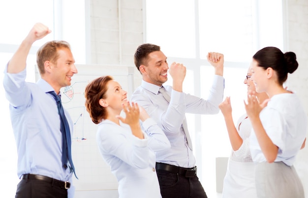 картина счастливой бизнес-команды празднует победу в офисе