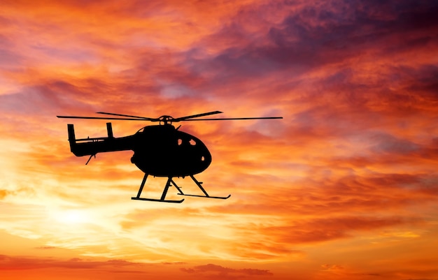 Picture of helicopter at sunset. Silhouette of helicopter on sunset sky.