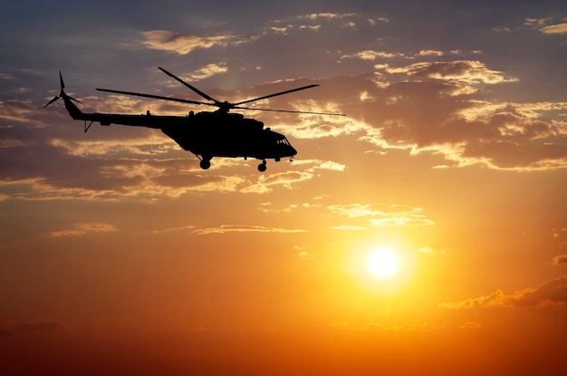 Picture of helicopter at sunset. Silhouette of helicopter on sunset sky.