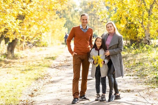 Picture of lovely family in autumn park, young parents with nice adorable kid playing outdoors, have fun on backyard in fall, happy family enjoy autumnal nature.