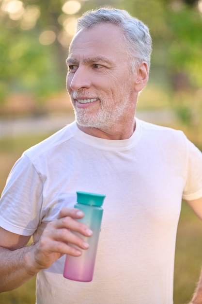 A picture of a man with a bottle of water in hands