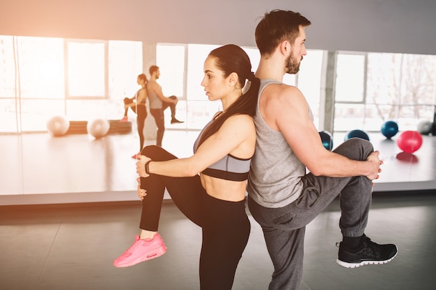 picture of man and woman standing back to back and pulling up one leg. They are trying to keep the balance of bodies on one hand.