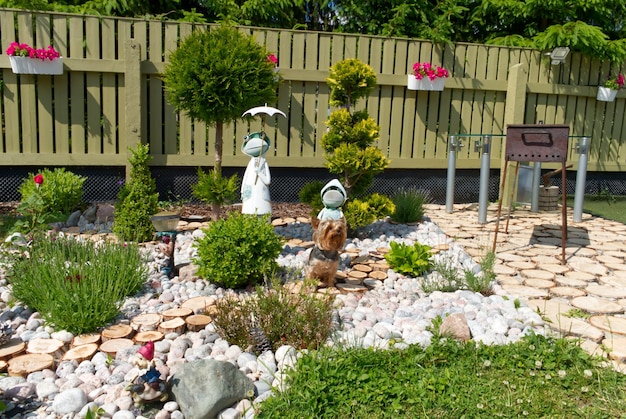 夏の自分の家の素敵な裏庭の写真居心地の良いデザインの花の木と小像