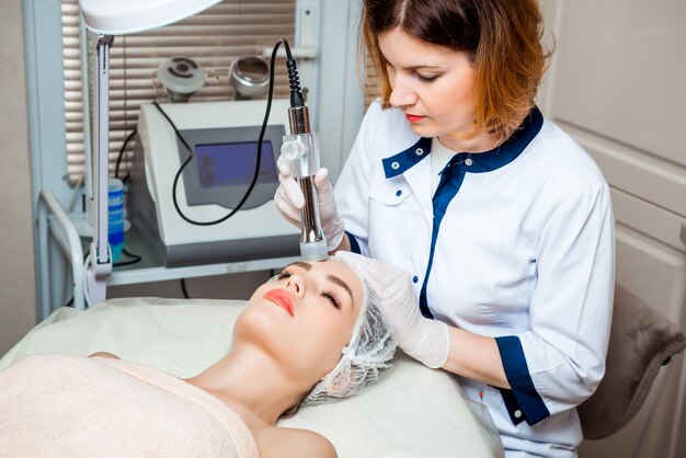 Picture of nice beautician doing oxygen therapy for young woman laying