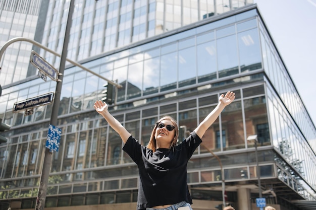 写真 手を上げて笑っている黒いtシャツの魅力的な女性の写真