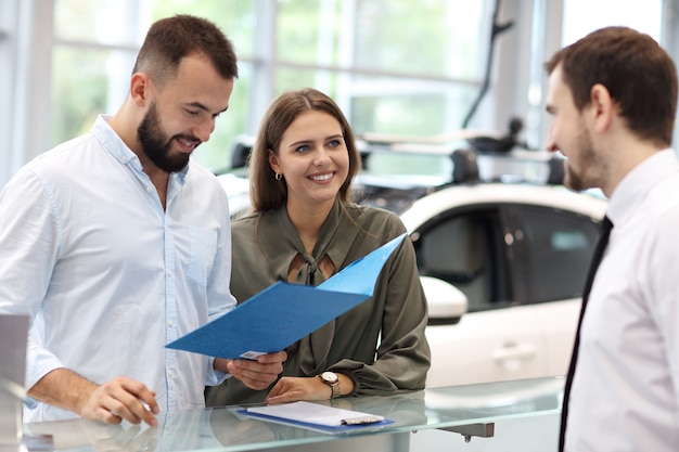 写真 若い魅力的な所有者にすべての車の機能を説明する自信を持って若いセールスマンの写真