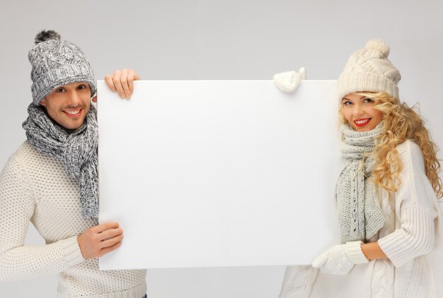 Фото Фотография семейной пары в зимней одежде, держащей пустую доску
