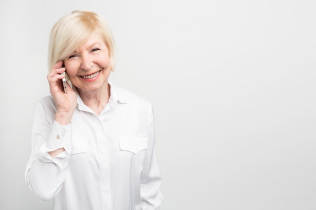 A picture of old lady using new phone. She likes to test it. This phone is her favourite one.