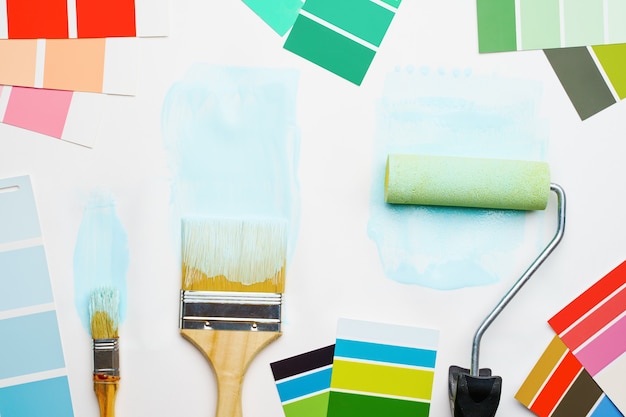 Immagine della tavolozza con colori blu e verdi, rullo, pennelli su sfondo bianco vuoto