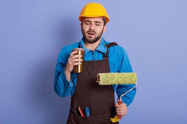 Picture portrait of sleepy tired construction worker closing his eyes