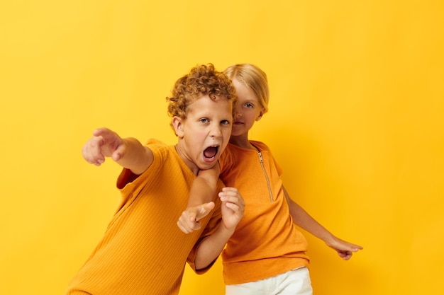 Изображение позитивного мальчика и девочки, обнимающихся модными детскими развлечениями на цветном фоне, необычно...