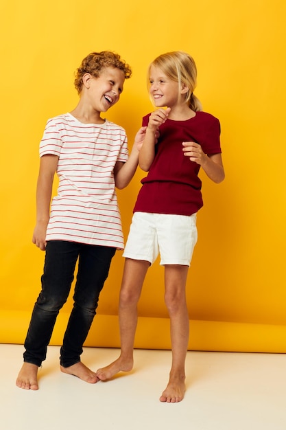 Изображение позитивного мальчика и девочки, обнимающихся модными детскими развлечениями на цветном фоне