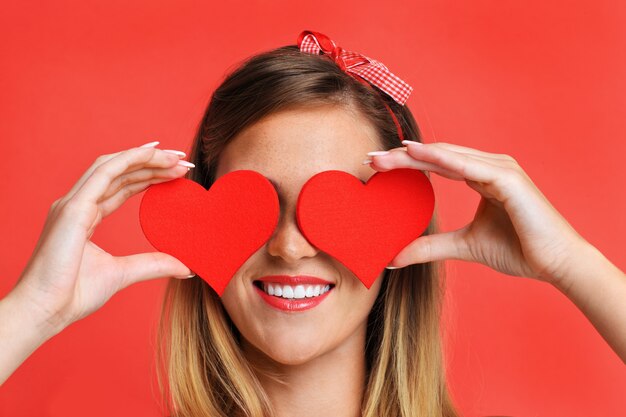 A picture of a sexy Valentine woman holding a heart over red background