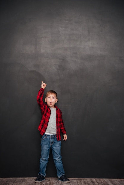 Picture of shocked little boy standing over chalkboard and pointing up