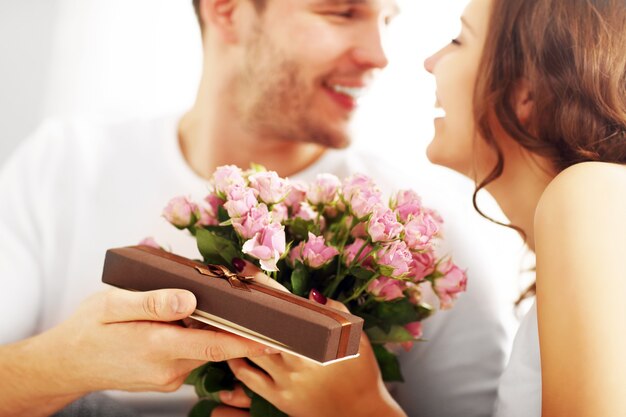 Picture showing man giving flowers and present to woman in bed