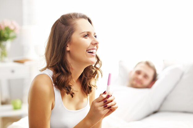 Picture showing woman with pregnancy test in bedroom