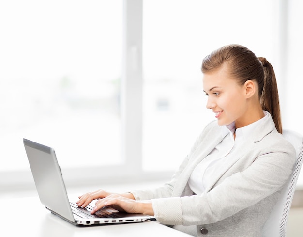 picture of smiling businesswoman with laptop in office