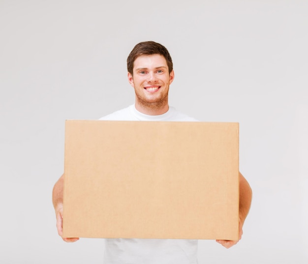 カートンボックスを運ぶ笑顔の男の写真