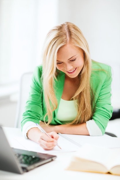 Foto di una studentessa sorridente che scrive sul taccuino