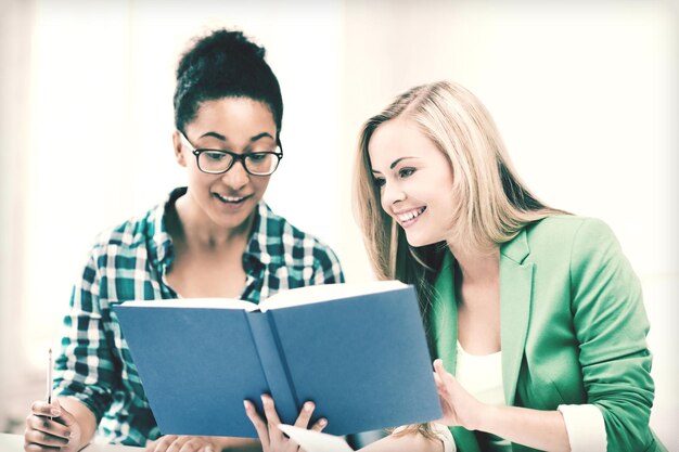 Foto foto di studentesse sorridenti che leggono un libro a scuola