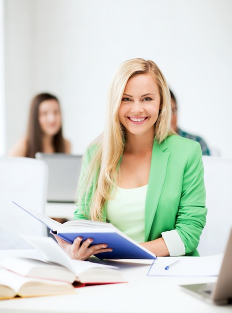 Foto di una giovane donna sorridente che legge un libro a scuola