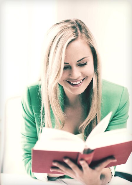 picture of smiling young woman reading book at school