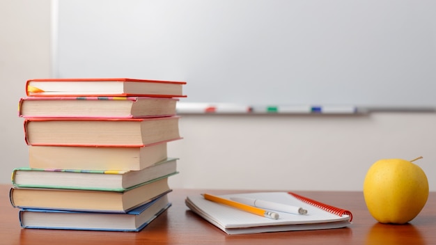 Picture of stack of books on the table against whiteboard