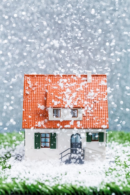 Foto foto di casa giocattolo con neve che cade sul muro grigio