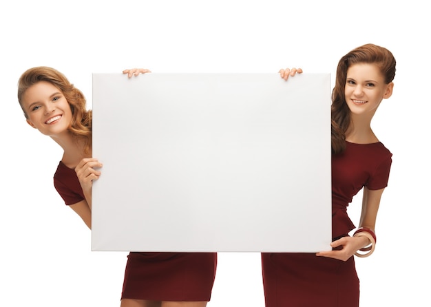 изображение двух девочек-подростков в красных платьях с пустой доской