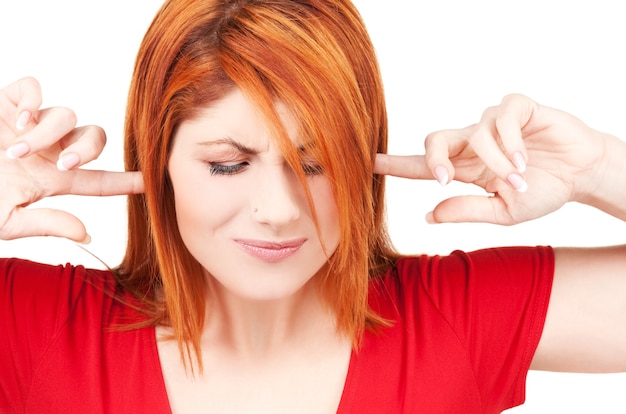 Photo picture of unhappy redhead woman with fingers in ears