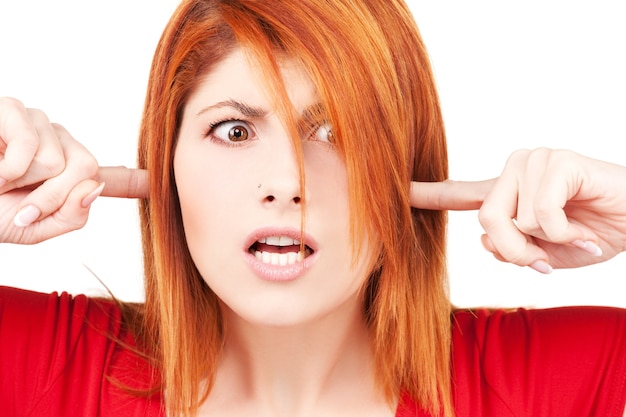 picture of unhappy redhead woman with fingers in ears