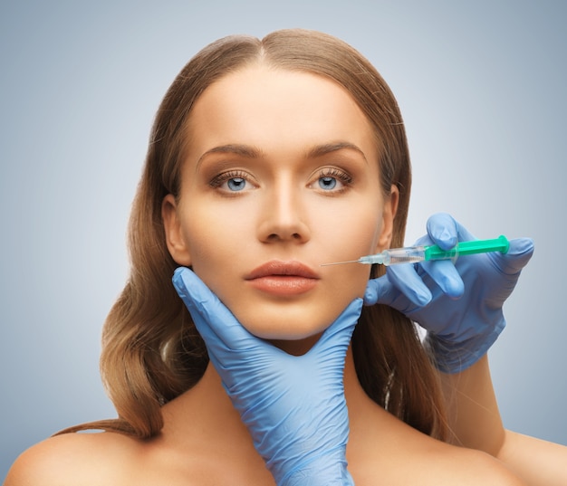 picture of woman face and beautician hands with syringe