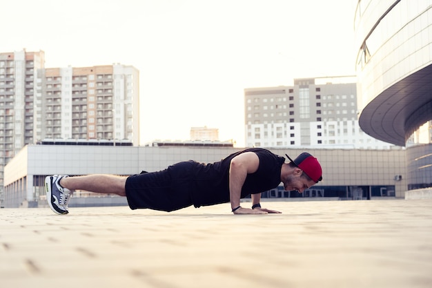 Изображение молодого спортивного человека, отжимающегося на открытом воздухе. Фитнес и упражнения на открытом воздухе в городской среде.