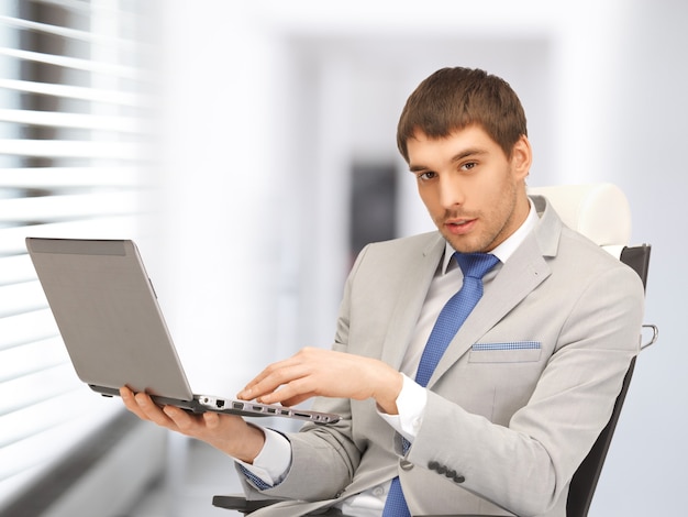 картина молодого бизнесмена, сидящего в кресле с ноутбуком