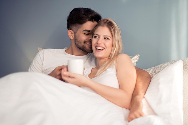 Picture of young couple drinking coffee in bed