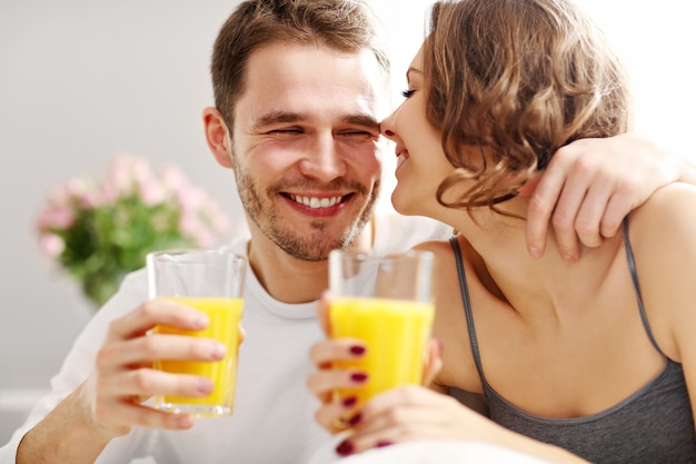 ベッドで朝食を食べる若いカップルの写真