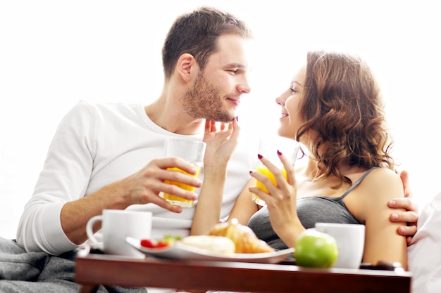 Picture of young couple eating breakfast in bed