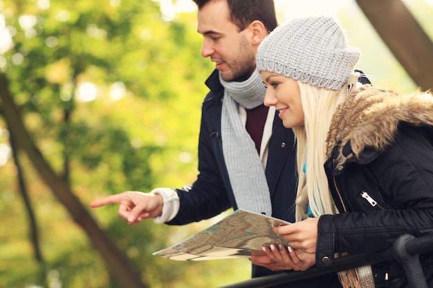 Фотография молодой пары с картой в парке