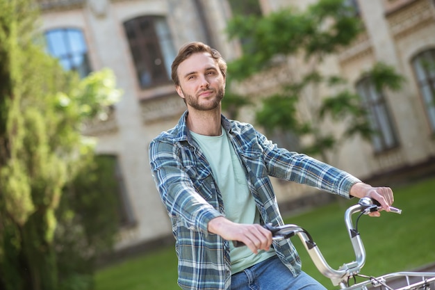 A picture of a young man in aplaid shirt on a bike