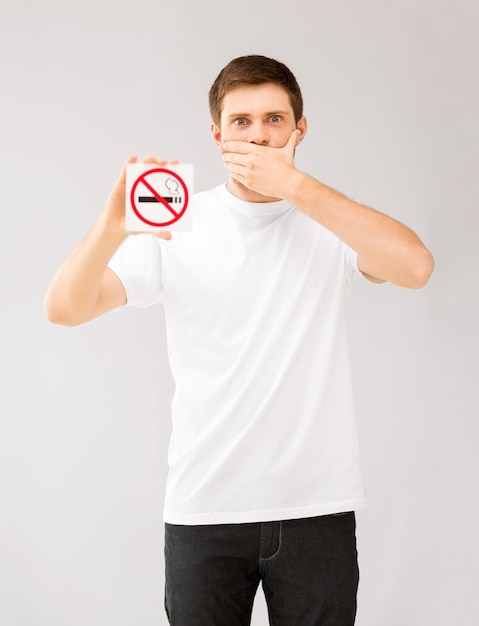 Photo picture of young man holding no smoking sign