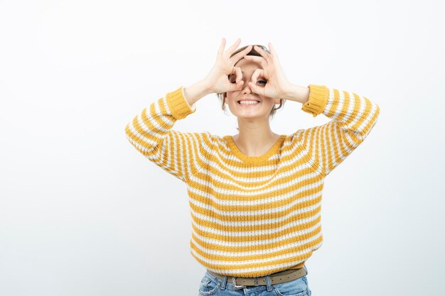 Foto immagine di un modello di giovane donna graziosa che guarda attraverso il gesto del binocolo. foto di alta qualità