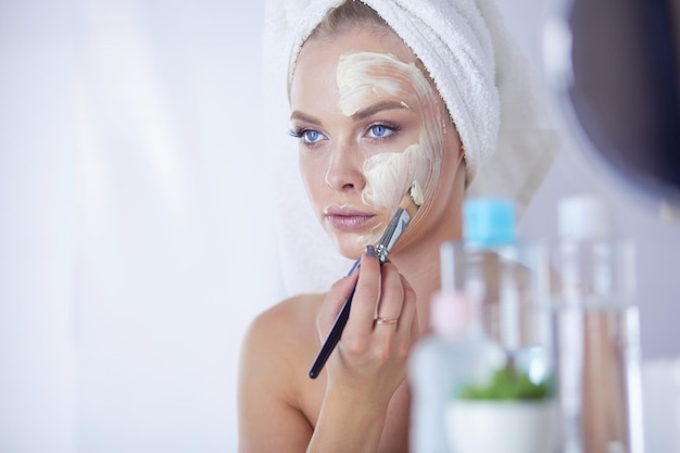 A picture of a young woman applying face powder in the bathroom